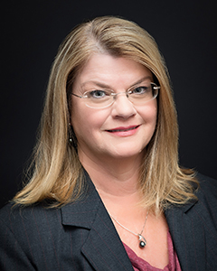 head and shoulder photo of Gretchen Bennitt wearing dark colored suit with black background